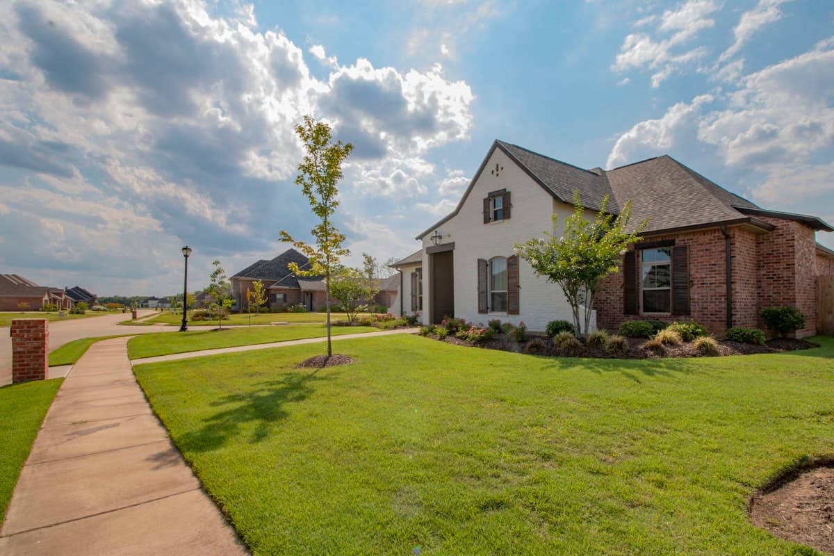 A two-story suburban home with a manicured lawn on a quiet tree-lined street